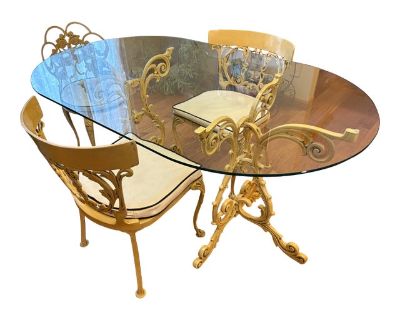 Enchanting vintage dining set featuring exquisite hand-crafted metalwork in the French Country style. This stunning ensemble includes an oval glass-top table and three matching side chairs, each adorned with elaborate floral and vine scrollwork that evokes the romance of European garden furniture. Table Details: Oval beveled glass top: 60 L x 36 Wx 3/8 thickness Ornate cast metal trestle base w...