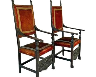 Pair of carved and upholstered Jacobean Armchairs. Chairs feature intricate hand-carving and are upholstered in rich velvet with embroidered trim and brass nailhead accents. The chairs also feature high rectangular backs with finial-topped posts, shaped arms, and sturdy square legs joined by stretchers for support. Each front stretcher is beautifully carved with scrolling foliage motifs. Arms, ...