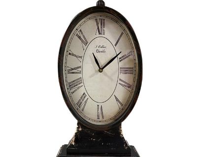 This tall oval table clock brings timeless charm to any room with its classic Roman numeral face and elegant black finish. Marked J. Collier Cheadle on the dial, it evokes the look of antique European timepieces with a gently aged aesthetic. Measuring 17.5 inches tall, this piece works beautifully on a mantel, entry table, or bookshelf. Its vintage-inspired design complements a range of interio...