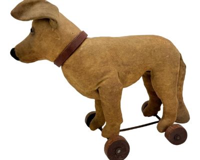 A rare and finely constructed early 20th-century German pull toy dog, attributed to the Steiff company or a Thuringian workshop operating in the Steiff tradition, circa 1900 1915. The figure is rendered in light tan twill fabric over a softly stuffed body, with shaped and stitched legs and a proportionally elongated tail. The head is fully articulated and designed to turn in tandem with the fro...