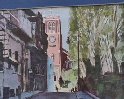 A picture of a water color style from 1960 by artist Boyd Hildebrand of a church in village. In a white frame that is 18" wide, x 14" tall. Two views of same, shown above.