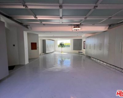 Blue Jay Way. LEASE TERM TO BE FOR NO LESS THAN ONE YEAR + ONE DAY. AVAILABLE FURNISHED OR UNFURNISHED. Inspired by some of the greatest Art Deco landmarks of our city, this rarified contemporary residence sits commandingly at the end of a gated private driveway flanked by an avenue of palm trees. The two-story entrance hall with its curving staircase leads to a sunken great room with disappear...