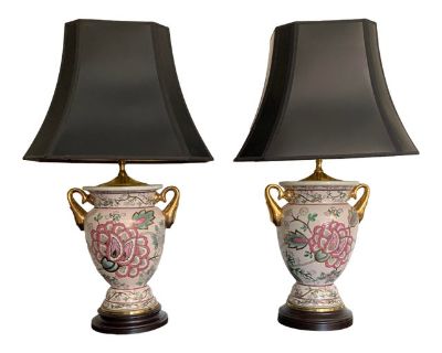 These double handled gilded vase lamps have an exquisite floral design of chrysanthemums in pinks and greens outlined in gold. Two raised gilded handles on the sides, a dark colored plinth on the bottom and a brass lid on top. Very elegant pair that will look incredible and will elevate any decor. Original finials and harps come with the lamps. Stunning black pagoda lamp shades with gold lining...