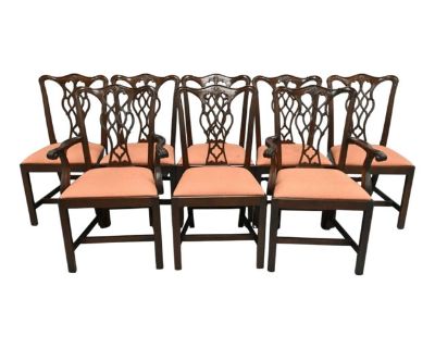 20th Century Set of Eight Chippendale-Style Mahogany Dining Chairs. There are two armchairs and six side chairs. Chairs feature intricately carved backs, a sturdy frame, and upholstered slip seats. The pierced splats feature interlacing ribbon motifs with foliate accents, surmounted by a gently curved crest rail. The armchairs have scrolling arms, while all chairs rest on straight, square legs ...