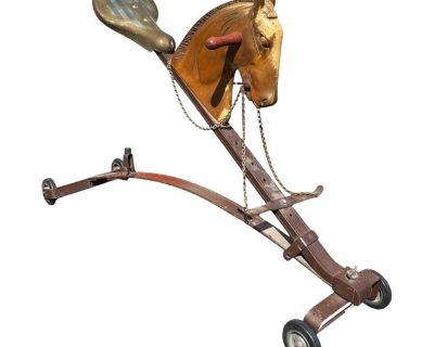 This antique children s ride-on horse is a rare find, showcasing the beauty of early 20th-century craftsmanship. The toy features a beautifully carved and painted wooden horse head with hand-painted details, complemented by a sturdy curved metal frame and rolling wheels. A vintage metal-style seat sits at the rear, giving it both function and nostalgic appeal. Complete with chain reins and orig...