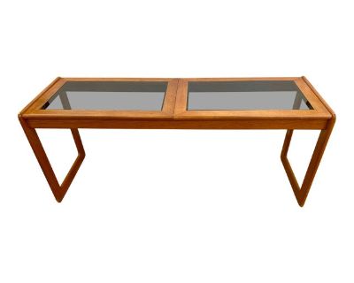 Mid-century Danish modern console table is a striking example of Scandinavian craftsmanship, blending warm teak wood with sleek, minimalist lines. Its elegant geometric base and smoked glass insets create a functional statement piece that radiates timeless style.. Dimensions 60 W 19 D 25.5 H Styles Mid-Century Modern Table Shape Rectangle Period Mid 20th Century Country of Origin Denmark Item T...