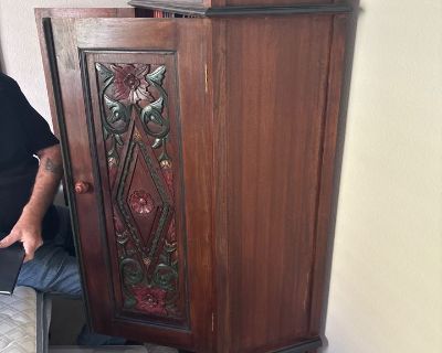 Teak Wood Ornate Indonesian Cabinet with two hand carved panels with floral motifs with green and red hues. Has 2 shelves. Small and gorgeous, in excellent condition. 40 x 15 1/2 x 60 . Local pick up. Delivery available by a third party for a min $100 depending on location and floor