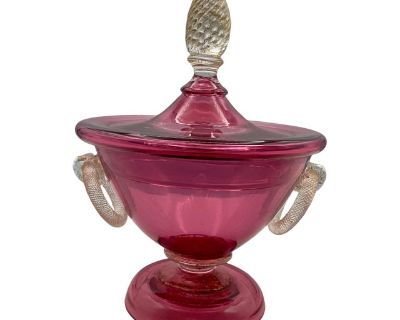 The Murano Cranberry Glass Neo Classical Lidded Jar is an exquisite piece of antique glass craftsmanship originating from Italy. Made by the renowned maker Murano, this original piece features a stunning cranberry color and elegant Neo-Classical style. With an age of post-1940, this lidded jar is a beautiful addition to any collection of antiques, showcasing the intricate artistry and craftsman...
