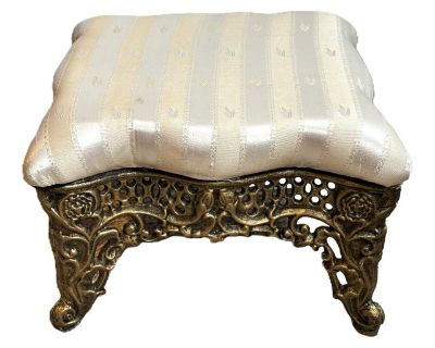 This Victorian-style cast iron footstool blends antique charm with modern sturdiness. Unmarked but likely made within the past 25 years, it beautifully replicates the ornate style of 19th-century cast iron furniture. The stool measures 13" x 13" x 8" high and weighs over 12 pounds, offering excellent stability and durability. The cast iron base features detailed scrollwork with a brushed gilded...