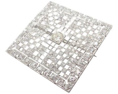 This vintage Art Deco brooch showcases timeless elegance in platinum, adorned with approximately 5 carats total weight of dazzling diamonds. The intricate square grid design reflects geometric sophistication, iconic of the 1920s era. A true estate treasure, this pin is both a luxurious statement piece and a collector s dream. Details: Metal: Platinum Measurements: 36.5mm x 37mm Weight: 14.4 gra...