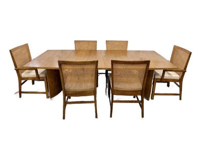 Striking mid-century modern dining set in beautiful condition, featuring a boat table paired with six caneback chairs, two arms and four side chairs. The table embodies clean MCM lines and warm wood grain, supported by dramatic curved pedestal bases that add sculptural presence to any room. The six chairs are crafted with sturdy teak wood frames, refined caneback panels, and neutral upholstered...