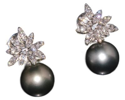 These earrings feature an elegant starburst diamond cluster design centered around perfectly matched natural Tahitian pearls. The rare combination of brilliant cut diamonds and exotic silver-grayish pearls offers timeless elegance and refined craftsmanship in one luxurious pair. The earrings showcase 1.06CTS of natural diamonds and 22.07CTS of genuine natural Tahitian pearls. The large, round T...