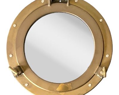 Classic maritime style meets timeless craftsmanship in this solid brass porthole mirror. Measuring 11.5 in diameter and 2.25 deep, this piece replicates the authentic form of a ship s window, complete with functional-style latches and rivet detailing around the frame. The mirror s warm brass tone has developed a natural patina, adding depth and vintage character. Ideal for coastal interiors, ba...